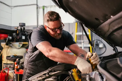 Mechanic working under the hood of a car in a repair shop
